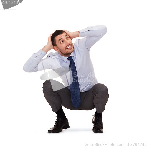 Image of smiling businessman crouching on the floor