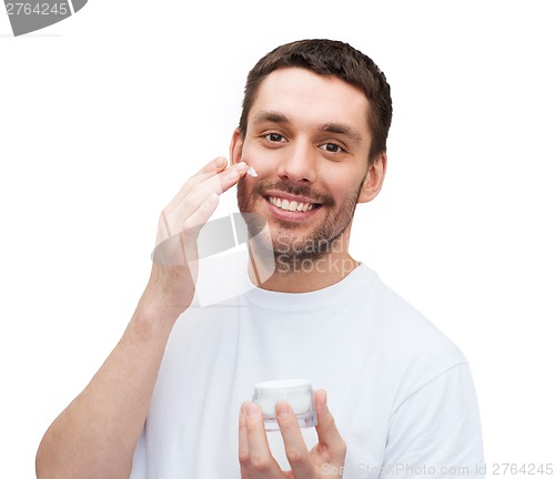 Image of beautiful smiling man applyin cream