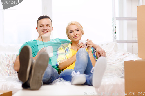 Image of smiling couple relaxing on sofa in new home