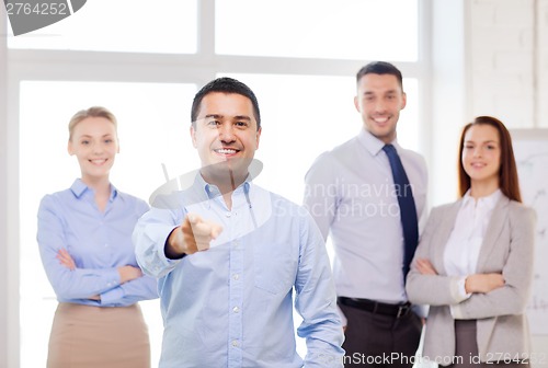 Image of businessman in office pointing finger at you