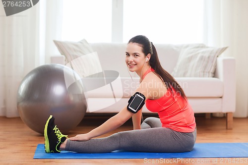 Image of smiling girl with armband execising at home