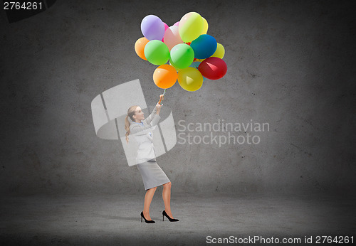 Image of businesswoman pulling down bunch of balloons