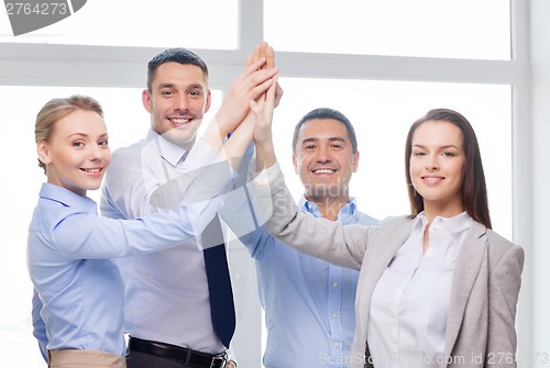 Image of happy business team giving high five in office