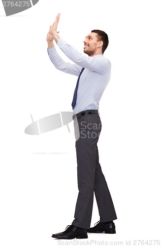 Image of smiling businessman pushing up something imaginary