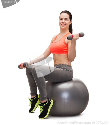 Image of teenager with dumbbells sitting on fitness ball