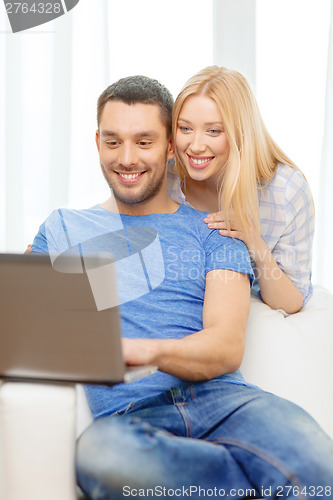 Image of smiling happy couple with laptop at home