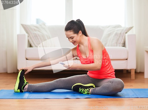 Image of smiling teenage girl streching on floor at home