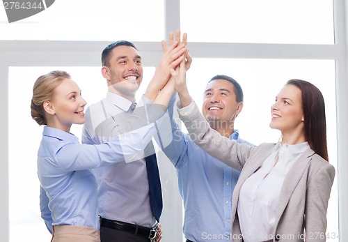 Image of happy business team giving high five in office