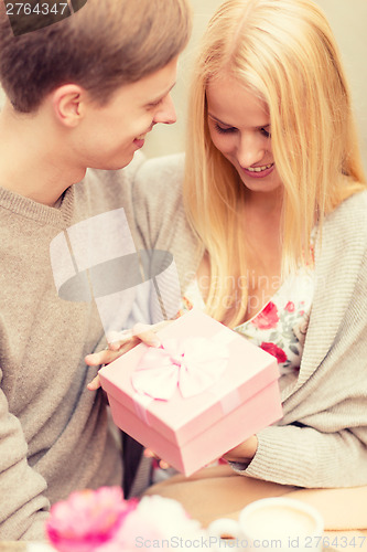 Image of romantic happy couple with gift in the cafe