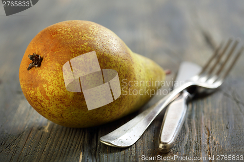 Image of Dessert knife, fork and ripe pear.