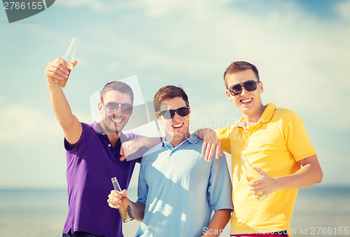 Image of friends on the beach with bottles of drink