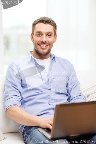 Image of smiling man working with laptop at home