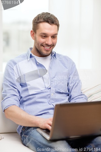 Image of smiling man working with laptop at home
