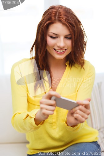 Image of smiling woman with smartphone at home