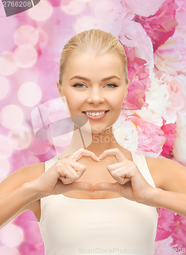 Image of smiling young woman showing heart shape gesture