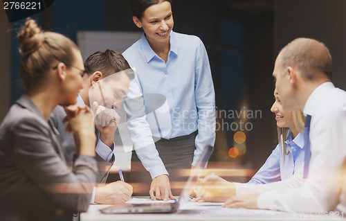 Image of smiling female boss talking to business team