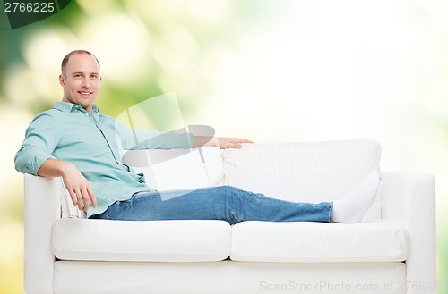 Image of smiling man lying on sofa