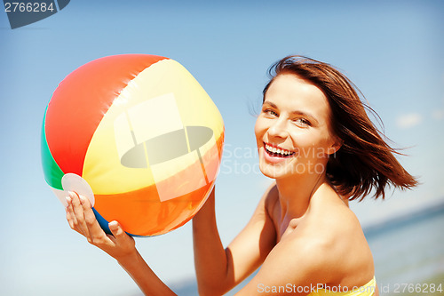 Image of girl in bikini playing ball on the beach