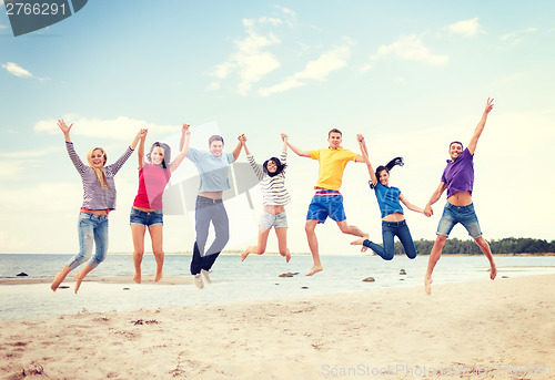 Image of group of friends jumping on the beach