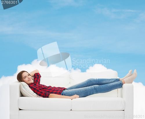 Image of smiling teenage girl lying on sofa