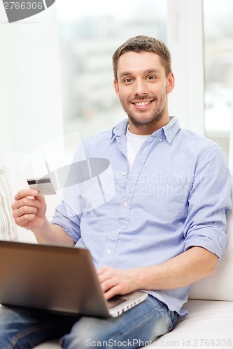 Image of smiling man working with laptop and credit card