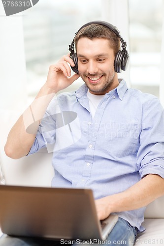 Image of smiling man with laptop and headphones at home