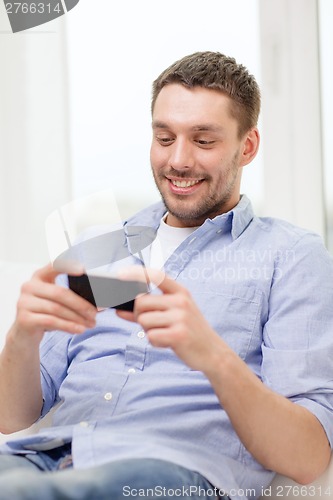 Image of smiling man with smartphone at home