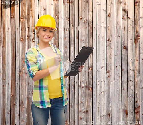 Image of smiling woman in helmet with clipboard