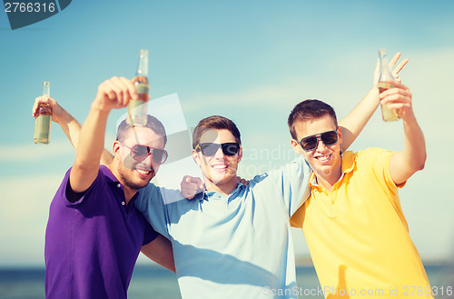 Image of friends on the beach with bottles of drink