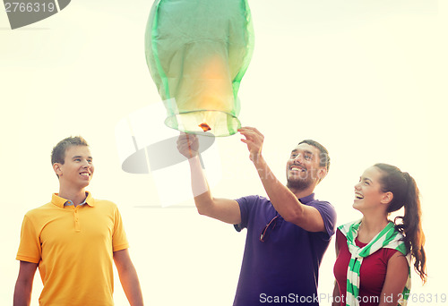 Image of friends with chinese sky lanterns on the beach