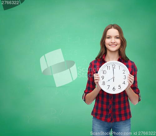 Image of young woman in casual clothes with wall clock