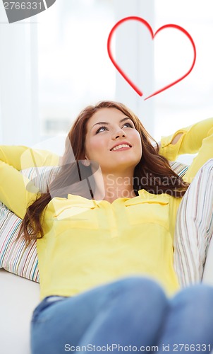 Image of smiling young woman lying on sofa at home