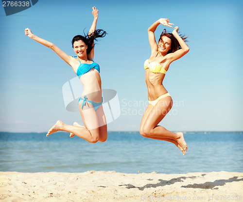 Image of girls in bikini jumping on the beach