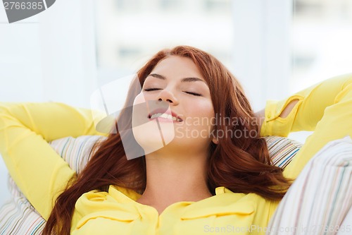 Image of smiling young woman lying on sofa at home