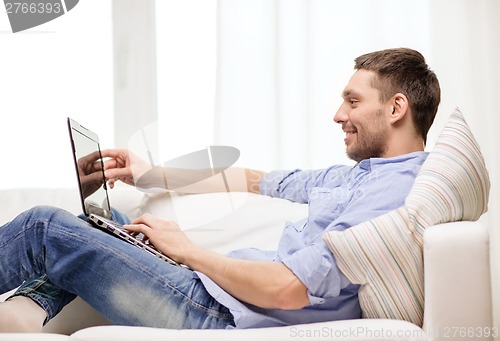 Image of smiling man working with laptop at home