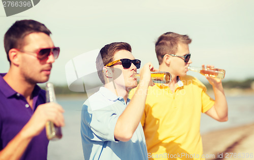 Image of friends on the beach with bottles of drink