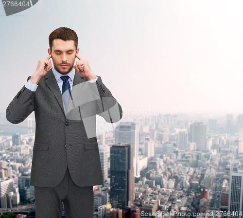 Image of annoyed businessman covering ears with his hands