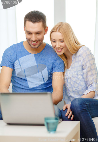 Image of smiling happy couple with laptop at home