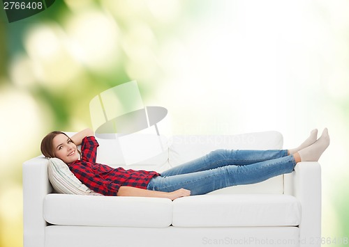 Image of smiling teenage girl lying on sofa