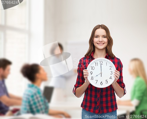 Image of young woman in casual clothes with wall clock