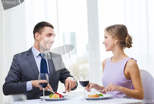 Image of smiling couple eating main course at restaurant