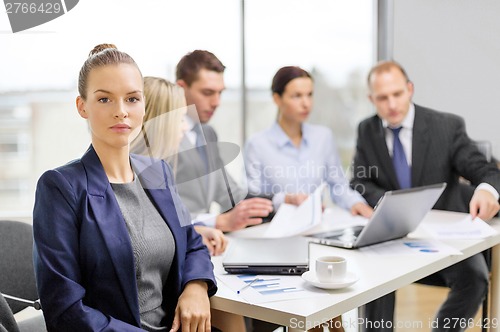 Image of businesswoman in office with team on the back