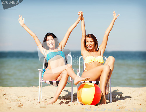 Image of girls sunbathing on the beach chairs