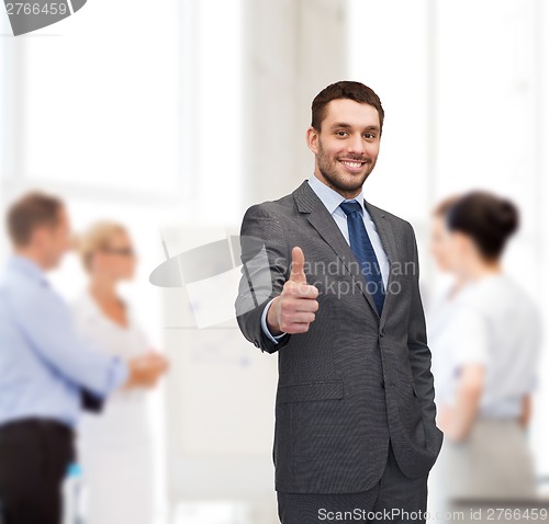 Image of handsome buisnessman showing thumbs up in office