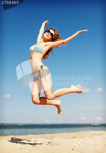 Image of woman in bikini jumping on the beach