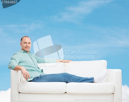 Image of smiling man lying on sofa