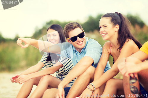 Image of group of friends pointing somewhere on the beach