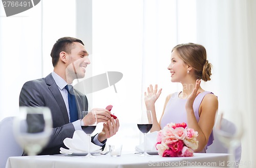 Image of man proposing to his girlfriend at restaurant