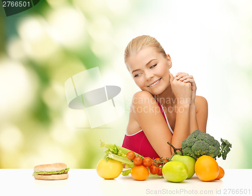 Image of doubting woman with fruits and hamburger