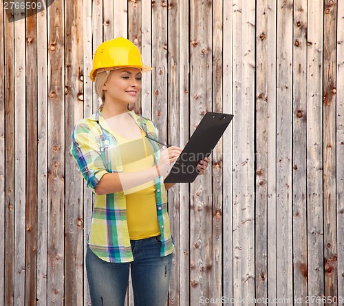 Image of smiling woman in helmet with clipboard